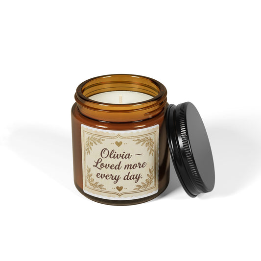 Amber glass jar candle with 'Olivia – Loved more every day' label, black lid open, on white background