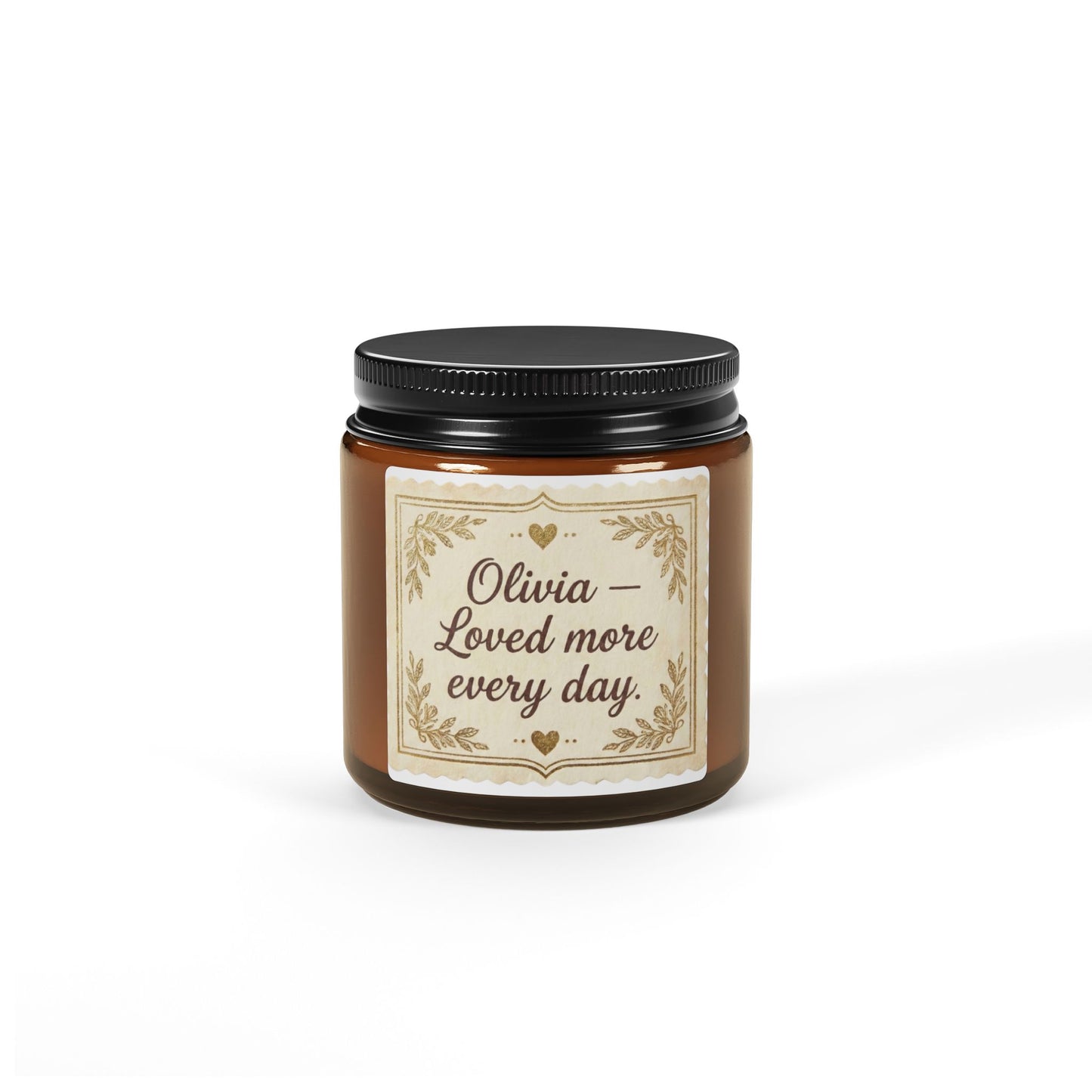 Personalized brown glass jar candle with 'Olivia – Loved more every day' label on white background