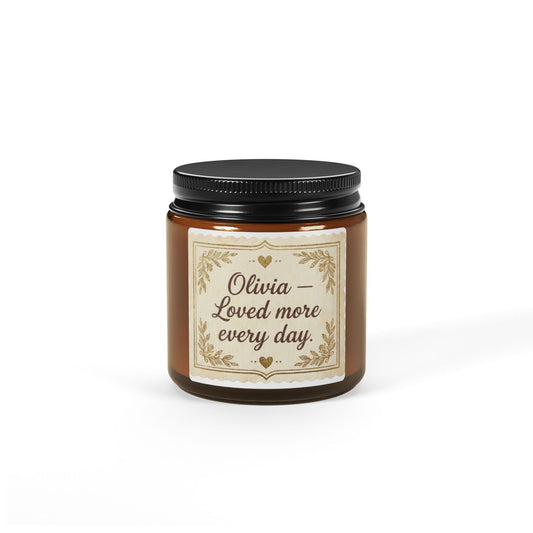 Personalized brown glass jar candle with 'Olivia – Loved more every day' label on white background