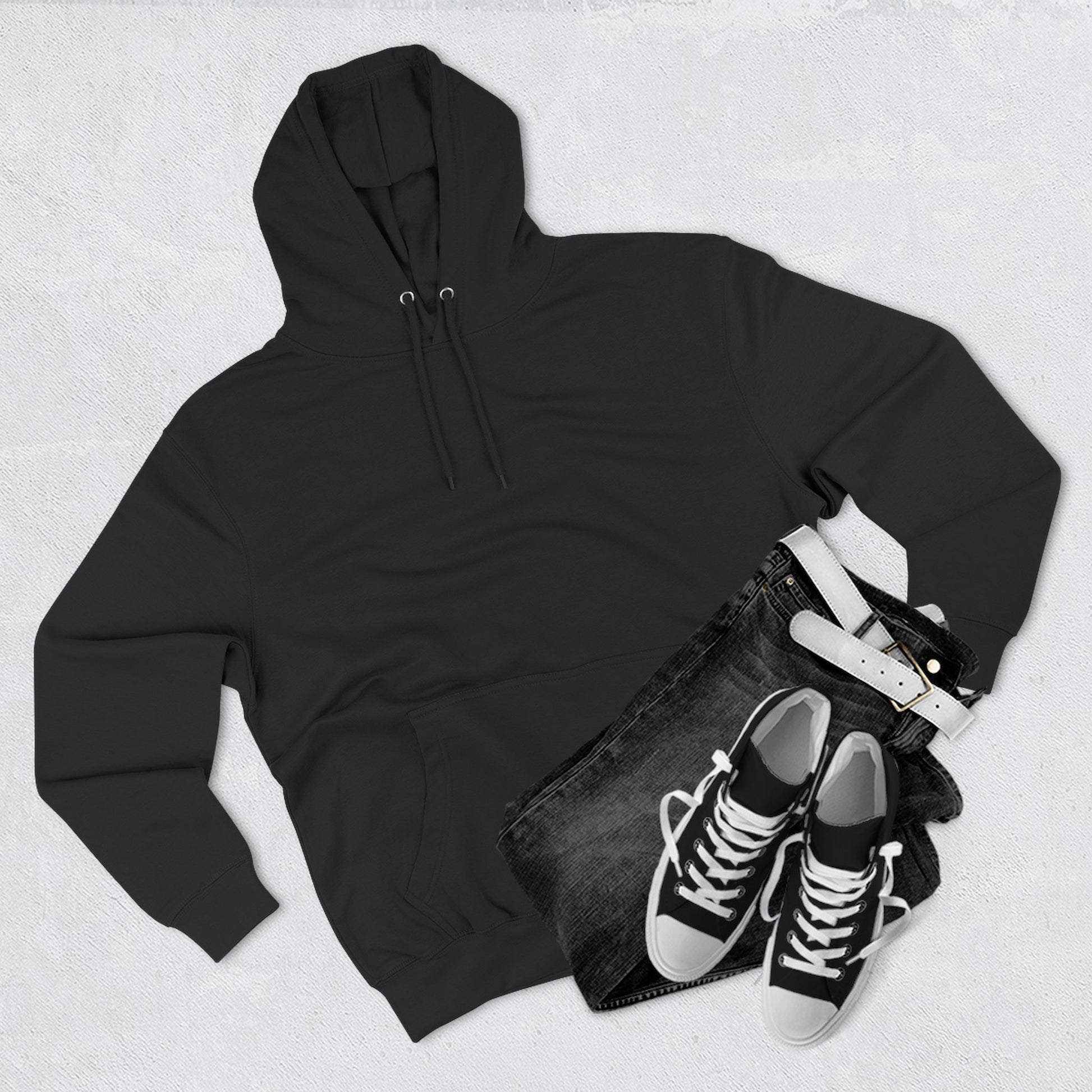 Black essentials hoodie, men's zip up jeans, white belt, and black sneakers flat lay